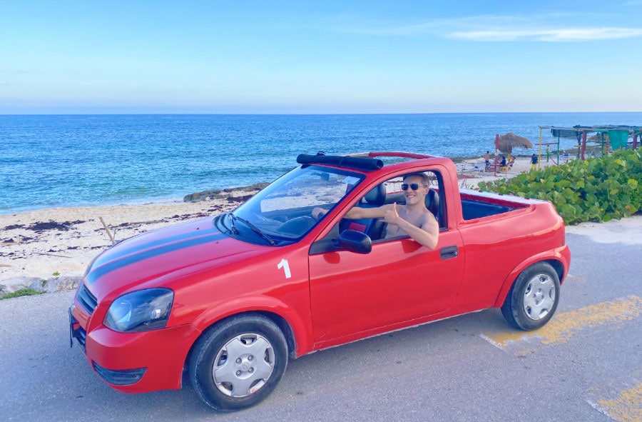 The author riding a convertible and the beach on his background