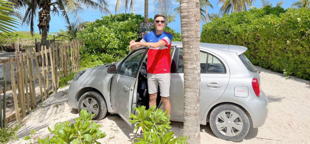 Nate on a beach in El Cuyo with a rental car
