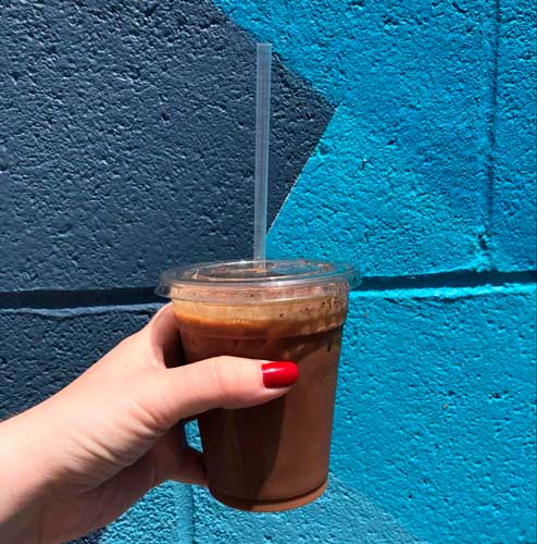 The author holding her drink from Retrograde Coffee