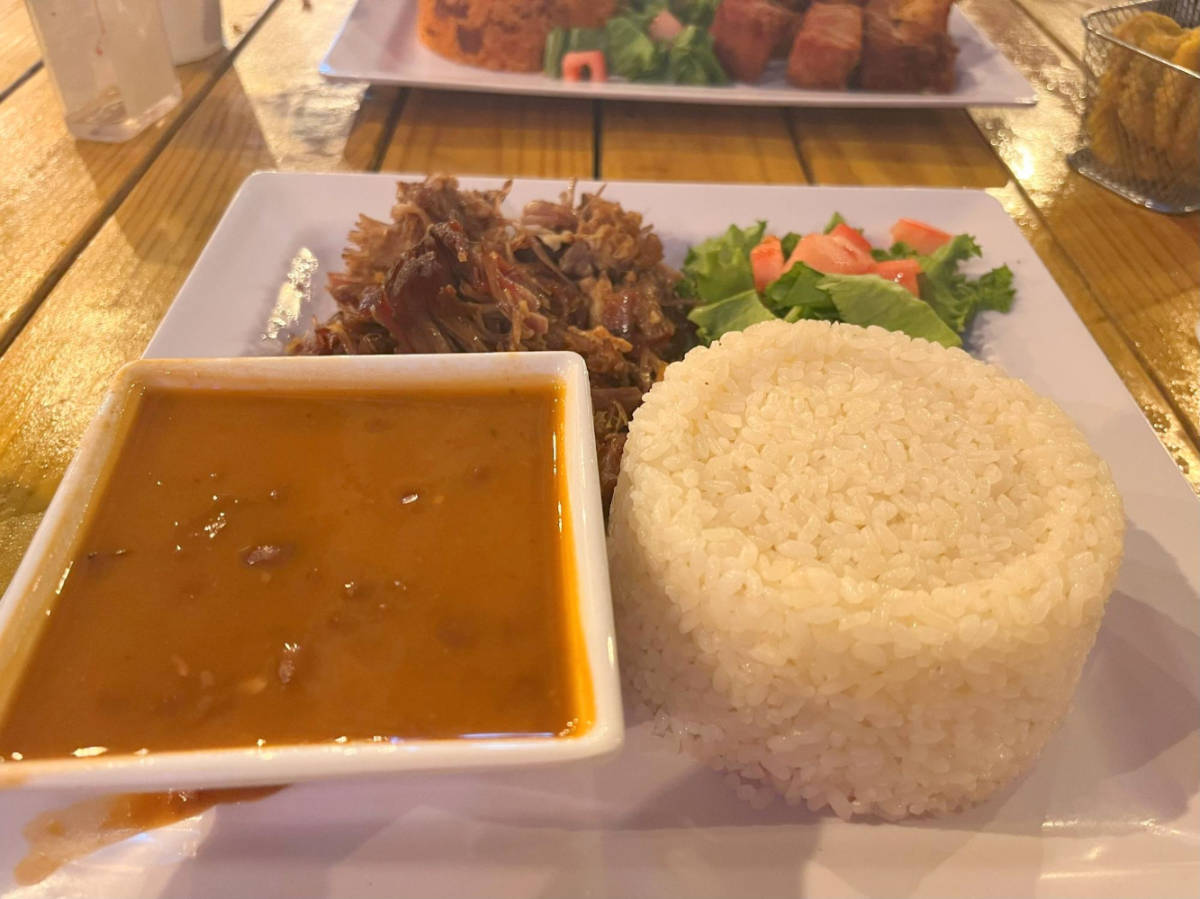 Rice, beans, and pork served on a plate in a restaurant