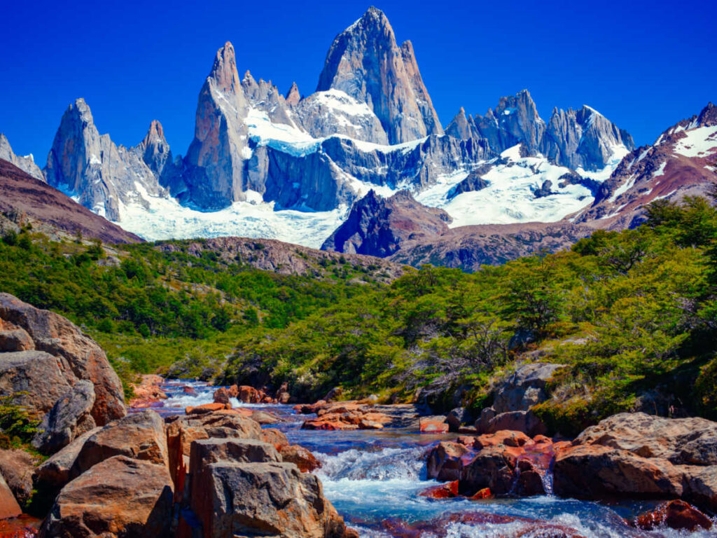 Scenic view of the snow on the mountain ranges and the blue river in El Chaltén