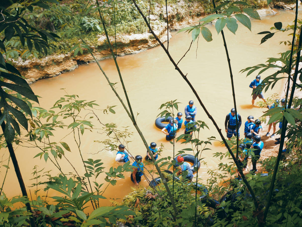 A group of people wearing life vests river tubing at Tanama river