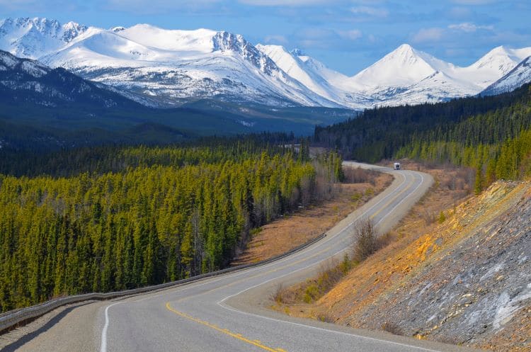 The Alaska Highway winds in amongst trees and mountains in the Yukon Territory