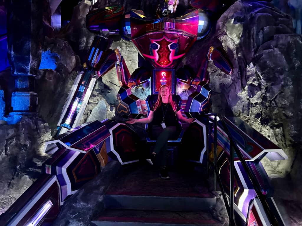 The author, Laura Falin sitting on a robotic themed chair at Meow Wolf Convergence Station