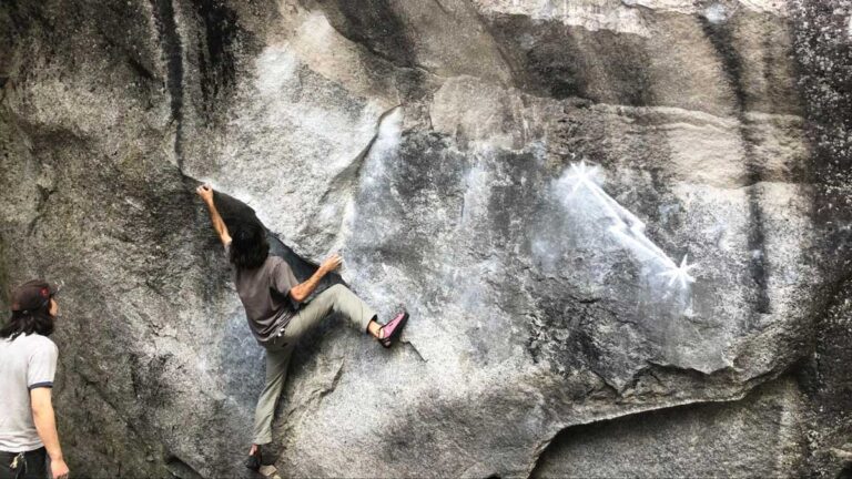 A man trying to climb a large rock