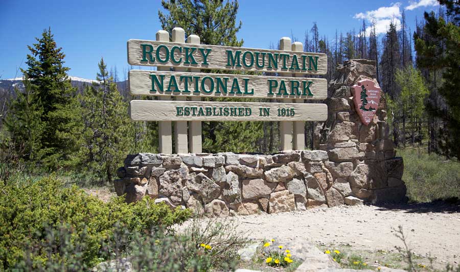 View of the Rocky Mountain National Park sign in Colorado under the clear blue sky