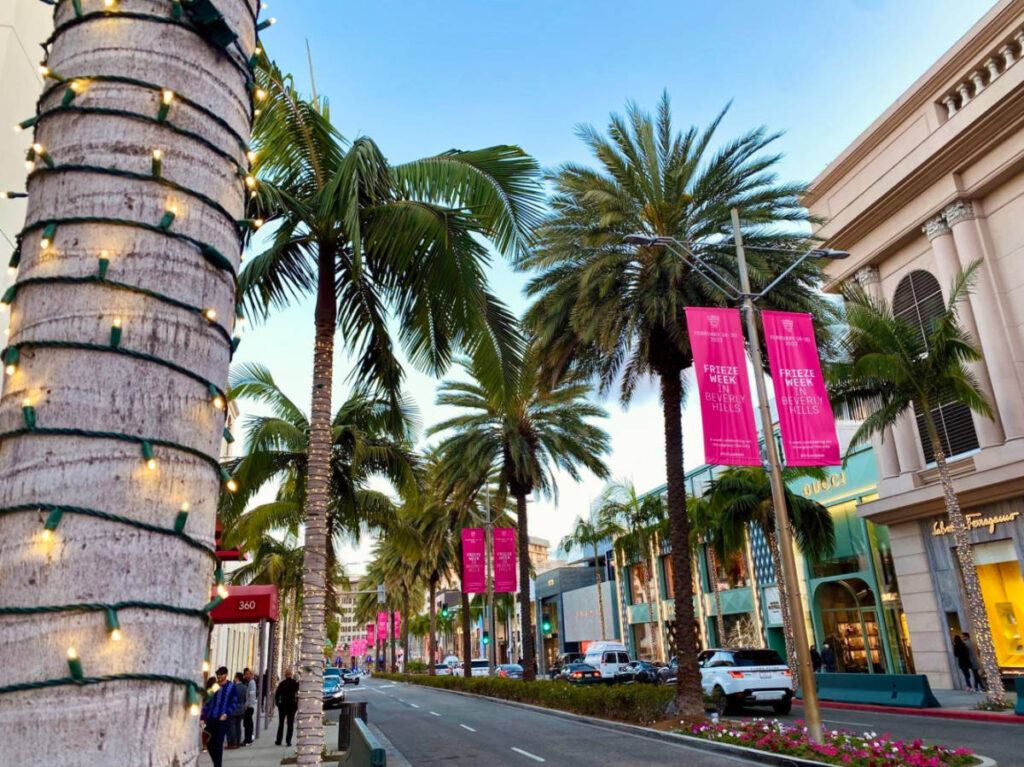 A palm-lined street with sidewalk in Rodeo Drive