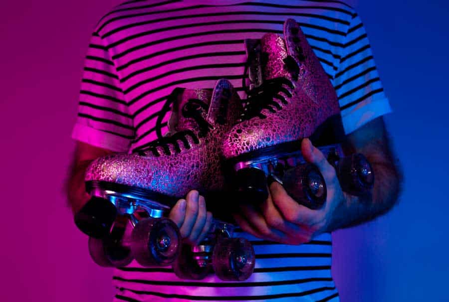 A man holding a retro roller skates with glitters on it