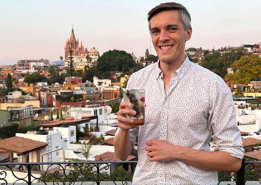 Nate holding his drink from a rooftop bar in Rosewood Hotel