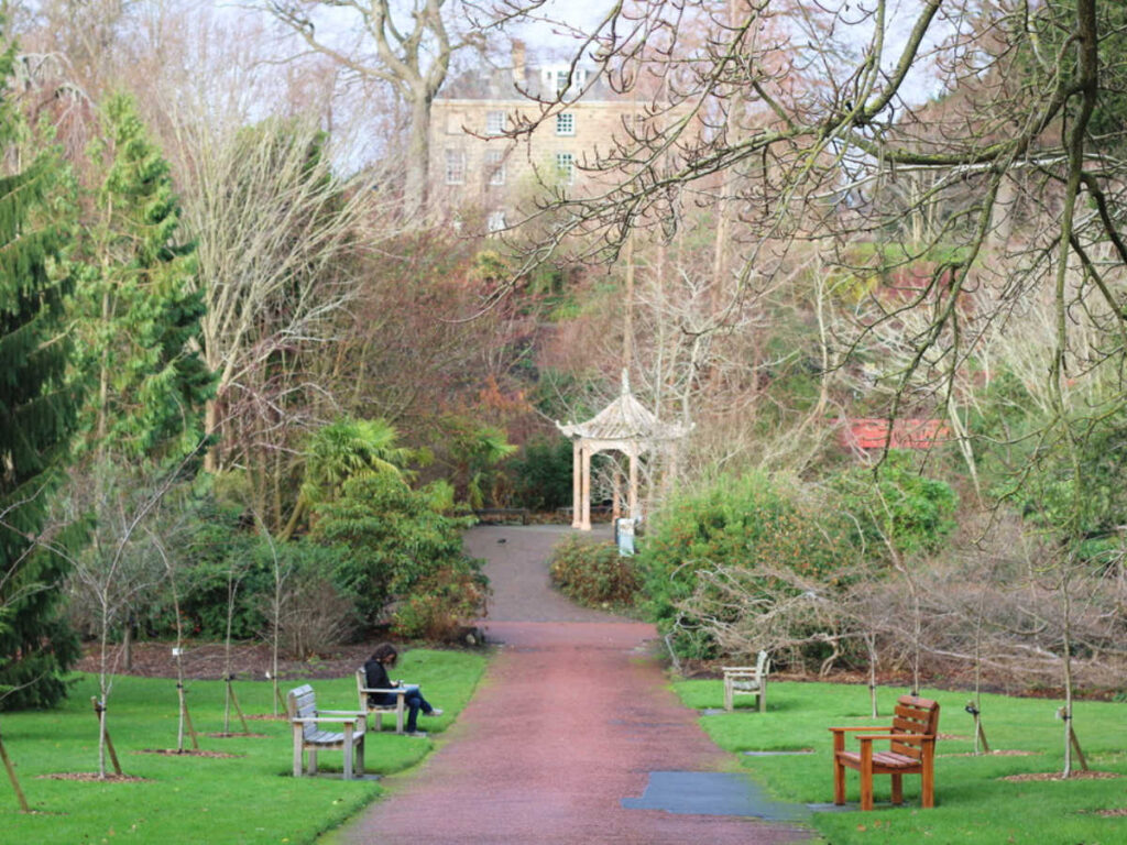 A woman reading at the bench in Royal Botanic Gardens Edinburgh