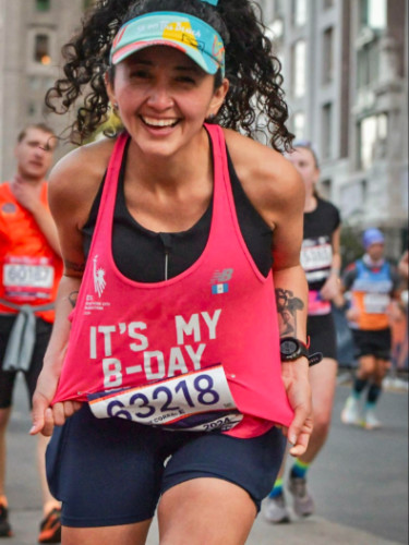 Runner showing her shirt and bib on the NYC Marathon