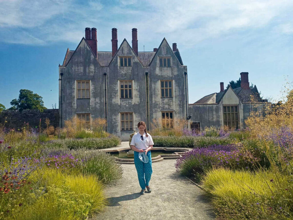 The author Ruthie walking outside the St Fagans Castle surrounded by greenery