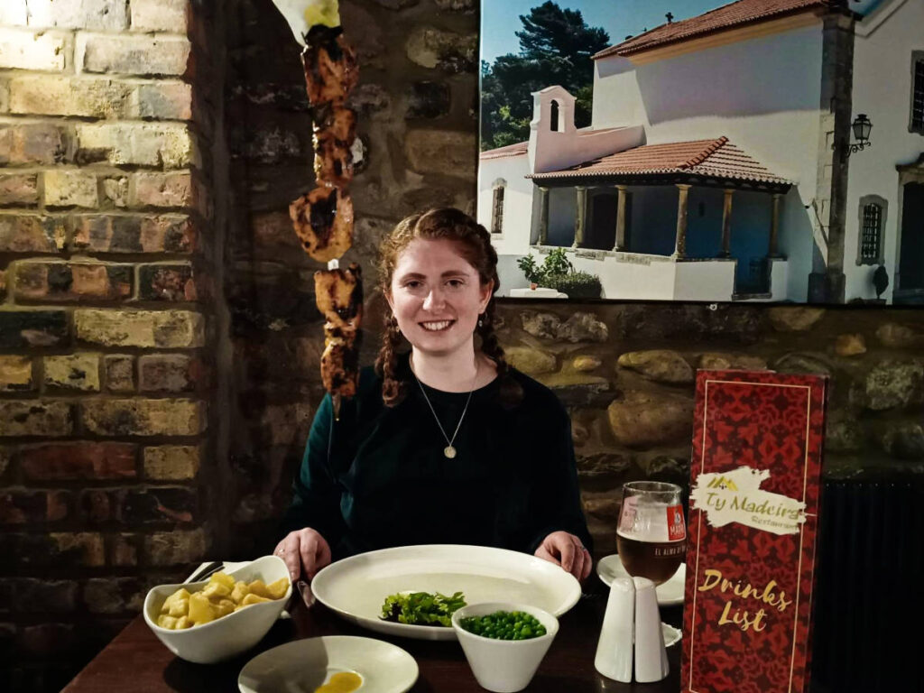 The author Ruthie Walters, sitting at the table with Chicken Espetada at Tŷ Madeira