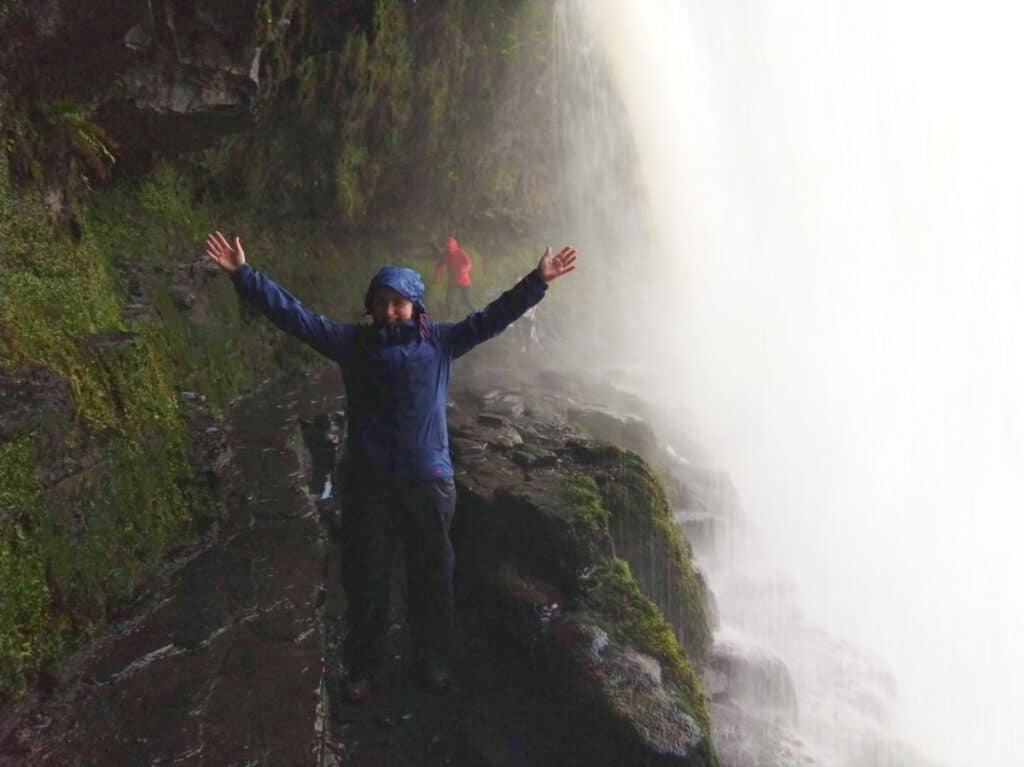The author Ruth Elizabeth Walters, posing at the rocky path behind the Sgwd-yr-Eira waterfall