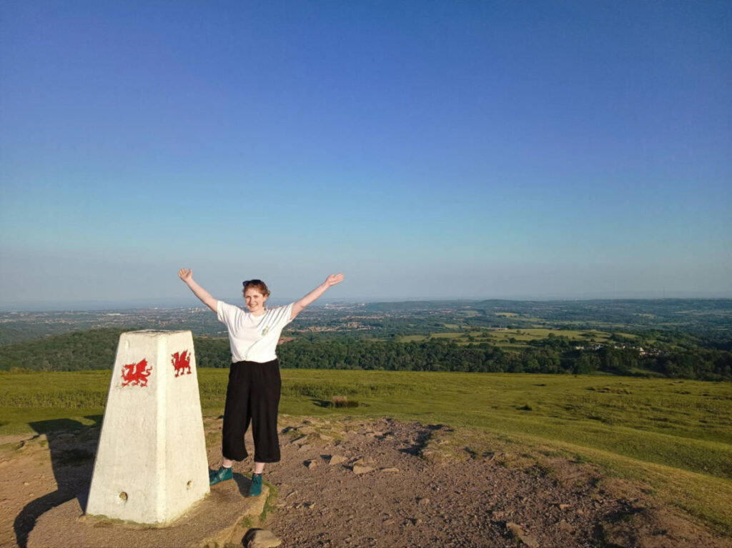 The author Ruthie Walters posing for a photo at the trig point on The Garth