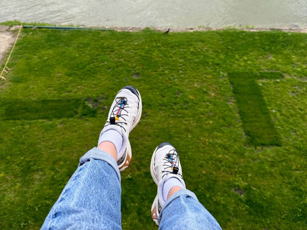 Author showing her Salomon Trail Runners on a green field