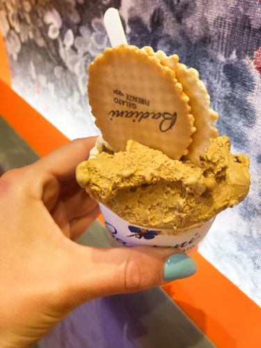 A hand holding a cup of salted butter caramel gelato