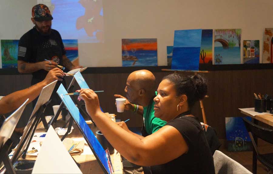 People focusing on painting while sipping on their drink