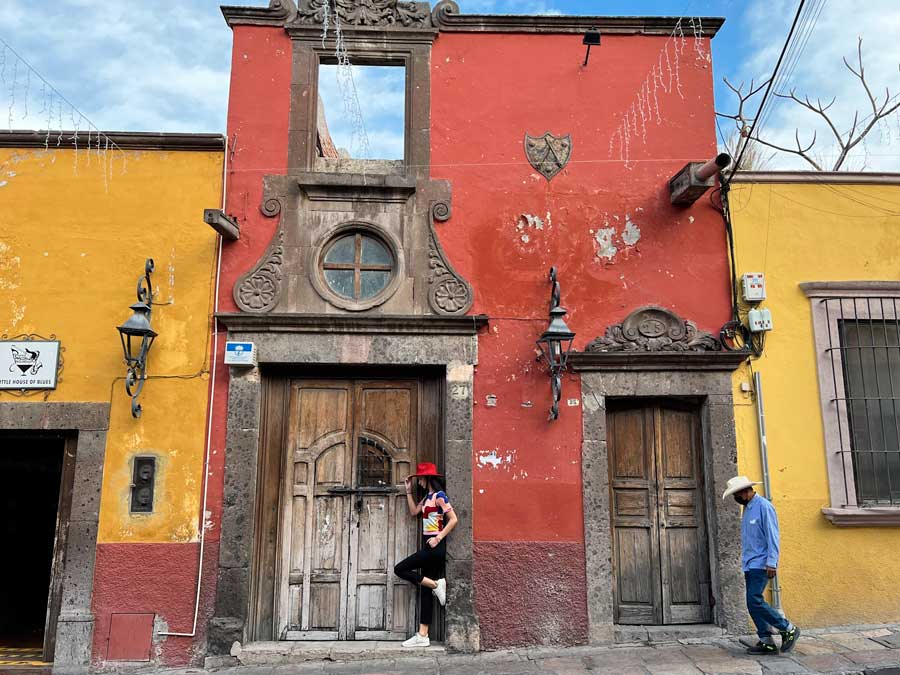 Clara posing for a picture with the colorful walls in San Miguel de Allende