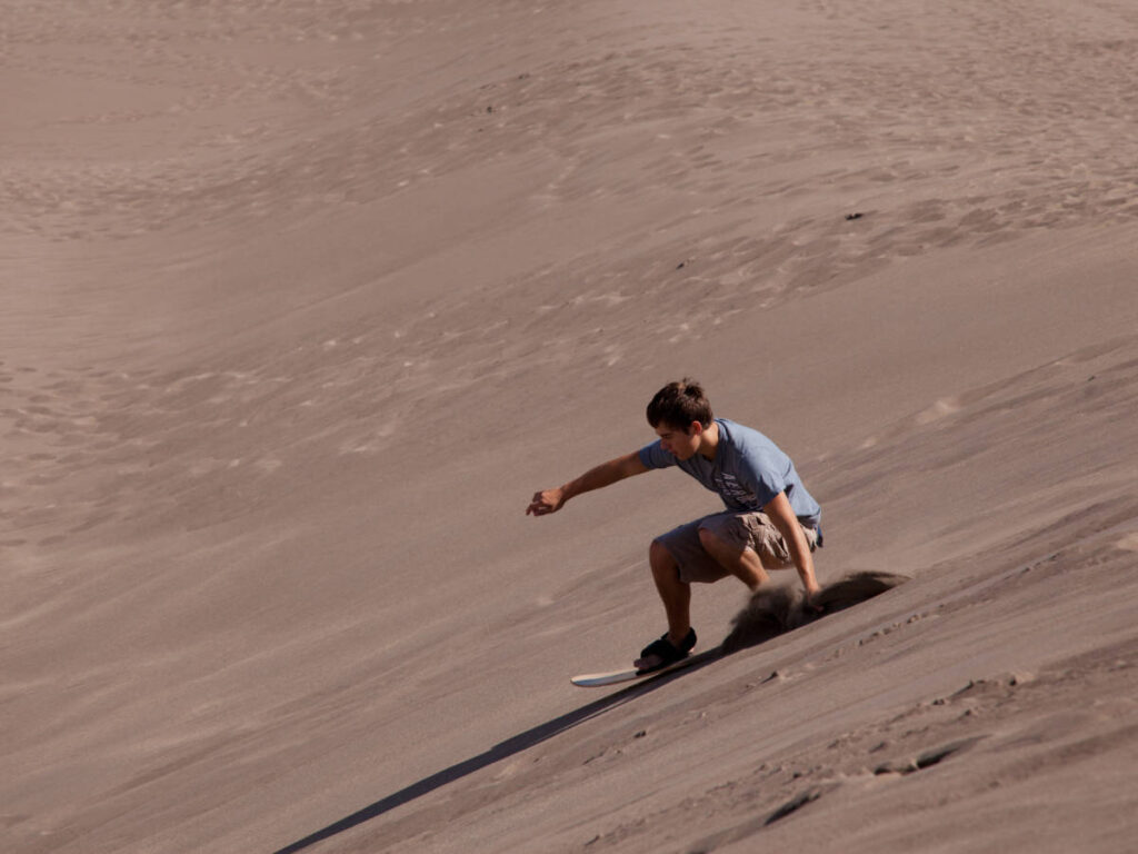 A man enjoying sandboarding at the Great Sand Dunes National Park