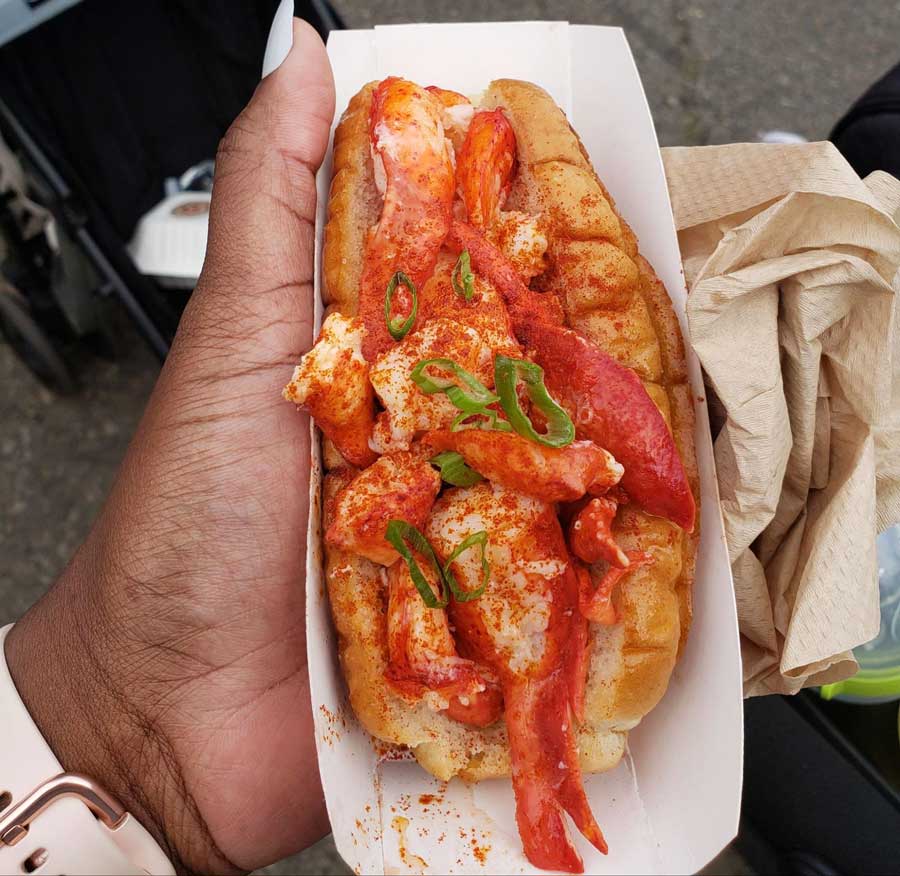 Travel Lemming writer Yvette holding a seafood sandwich from Smorgasburg