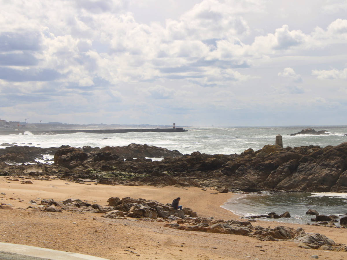 A man relaxing at the rocky and sandy beach with strong waves