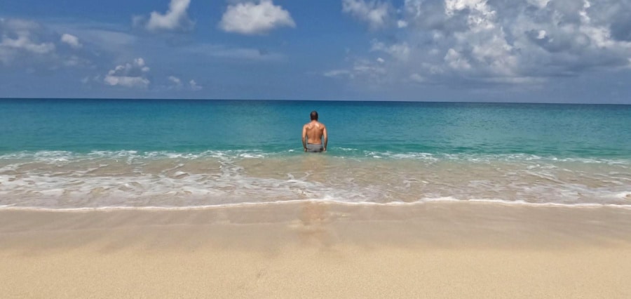 A man swimming in the serene waters of Sandy Point Beach