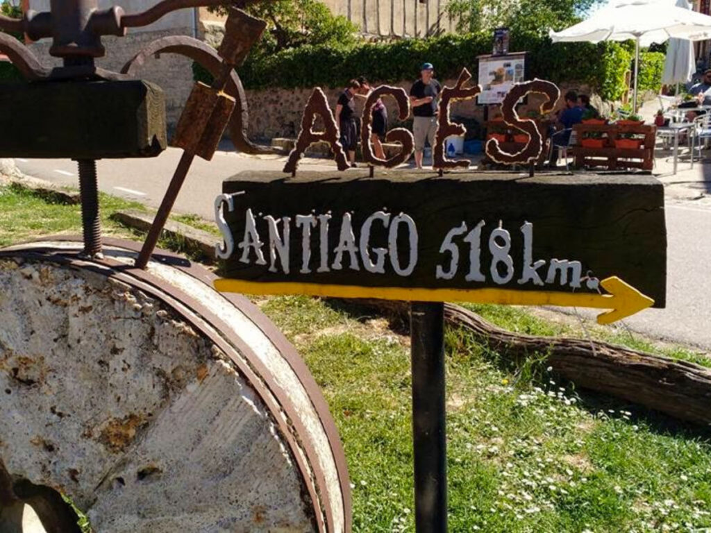 A sign reading 'Ages and Santiago' with yellow arrow pointing towards Santiago