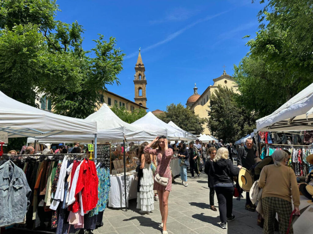 People strolls through Santo Spirito Market in Florence, surrounded by an array of shops