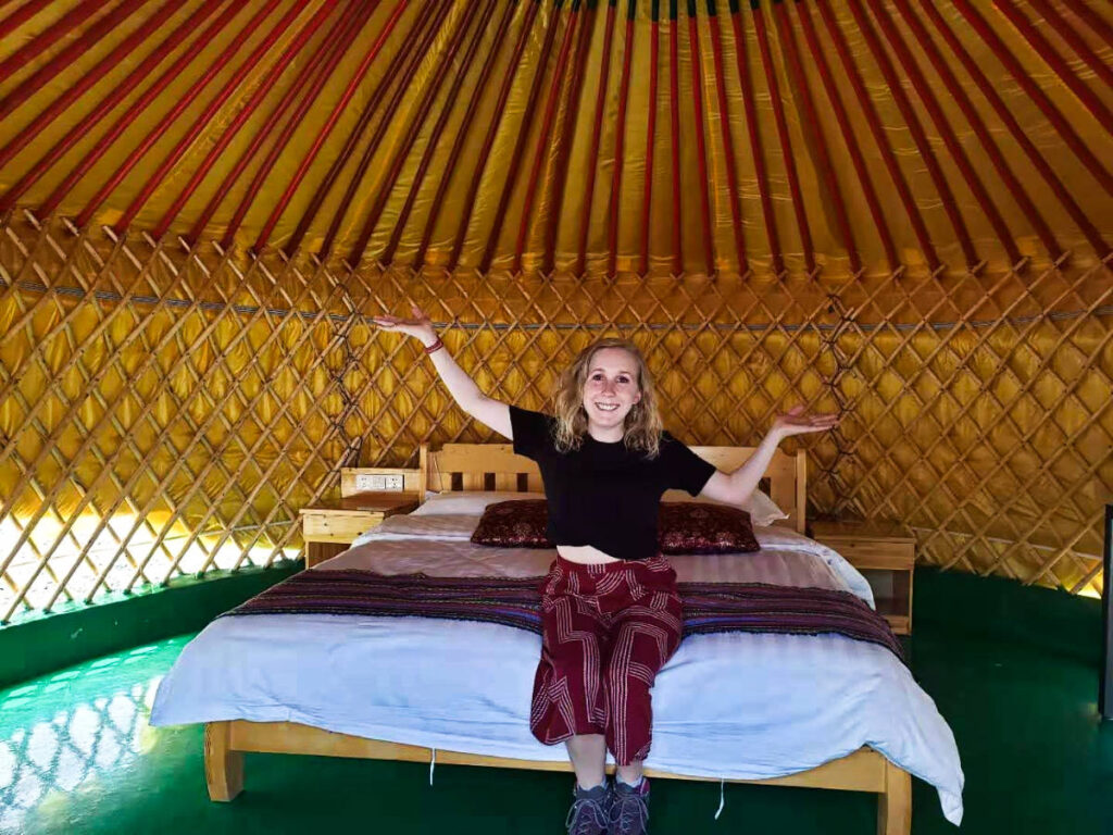 The author Sarah Heath sitting on the bed inside the yurt