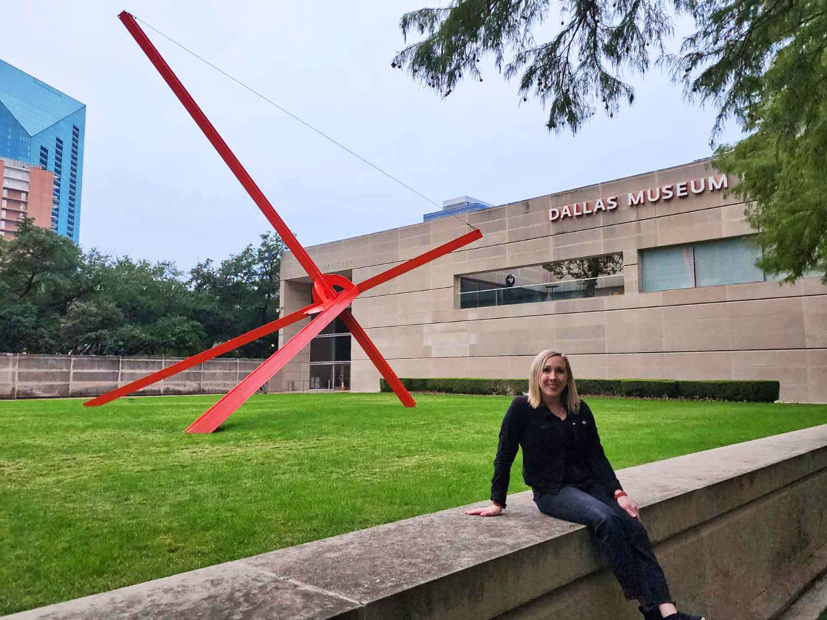 The author Sarah Heath, sitting in front of the unique sculpture on a lawn at the Dallas Museum of Art