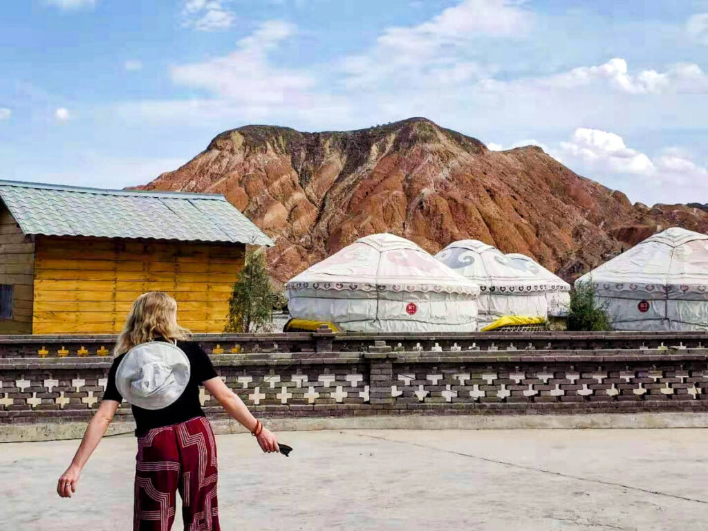 The author Sarah Heath, admiring the yurts and the rainbow mountains in the background