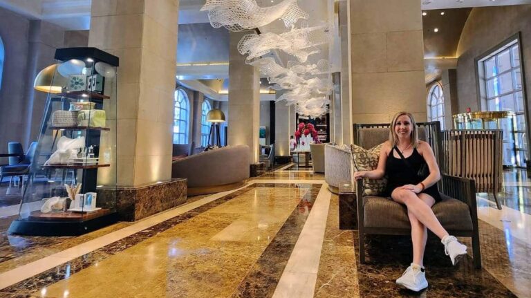 The author Sarah Heath sitting on a chair in the lobby of Hotel Crescent Court