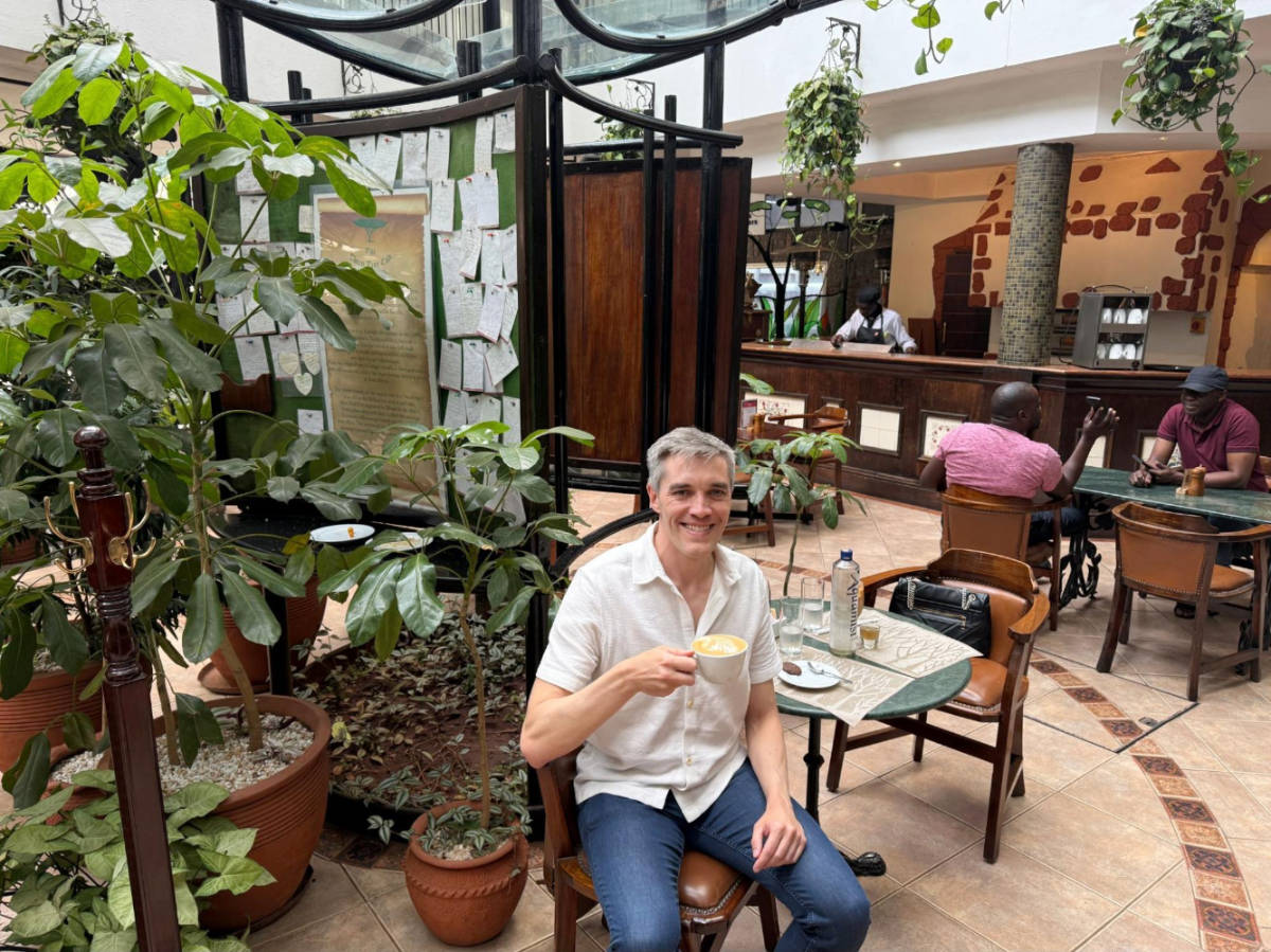 The author Nate Hake holding a cup of coffee at the Sarova Stanley hotel