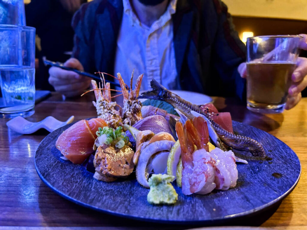 A plate of sashimi in front of a man in Mashiko