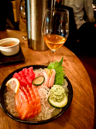 A plate of sashimi with a glass of orange wine at Brilliant Corners
