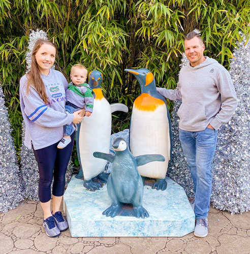 The author with her husband and son posing for a picture with the sculpture penguins