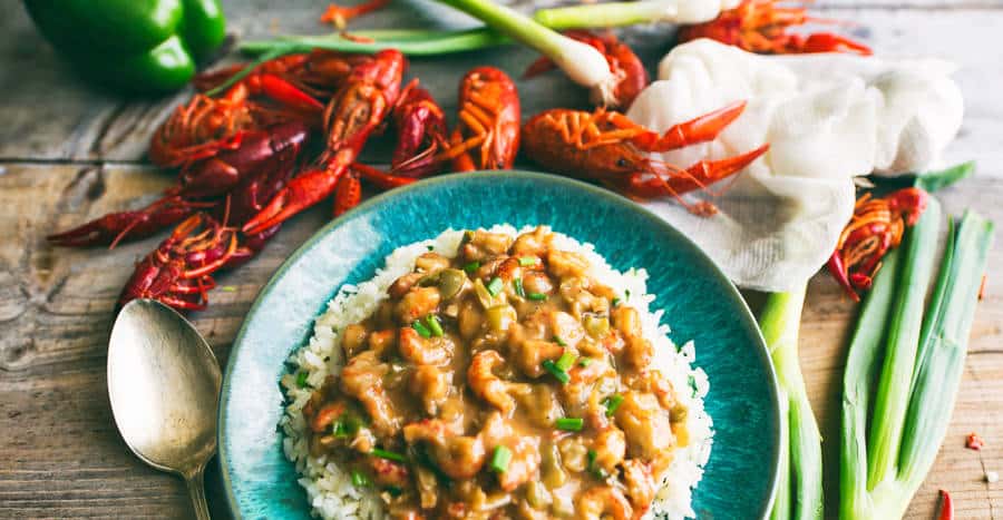 Closeup look of a turquoise blue plate with rice topped with crawfish étouffée