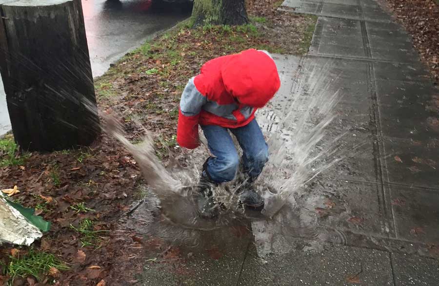 A kid jumping a puddle