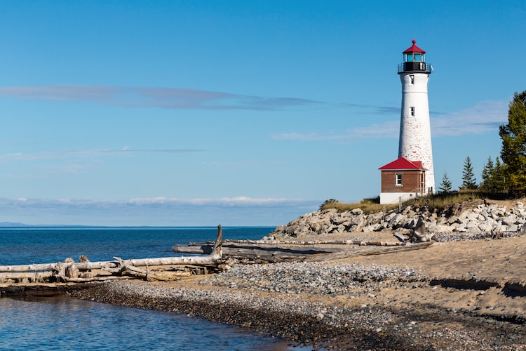 Red and White sheringham Point Lighthouse stands among blue water and waves on Vancouver Island