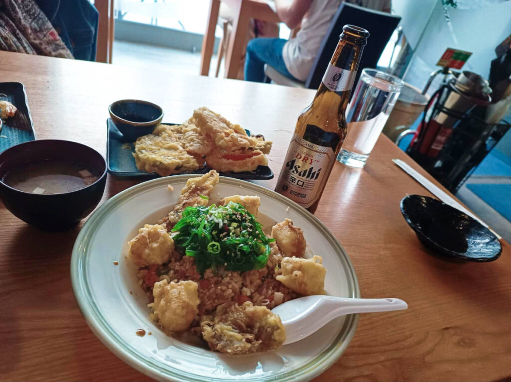 A plate with shiitake & tofu rice and a bottle of beer on the wooden table