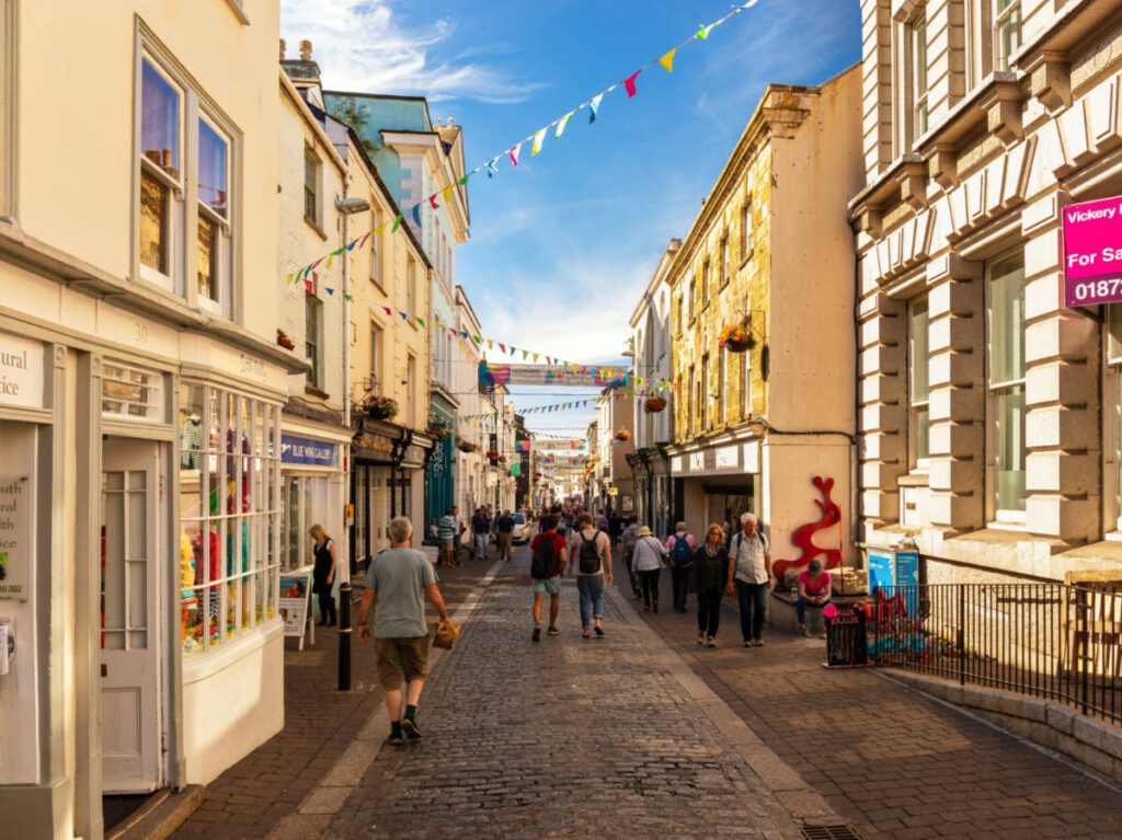 A small street surrounded by shops and people shopping around