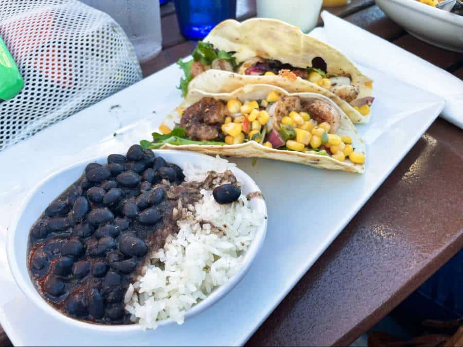 Two shrimp tacos and a plate of rice with black beans and sauce from Coconuts on the Beach