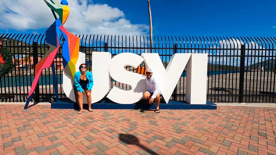 The author with his wife posing for a photo with a sign of USVI in Crown Bay Center