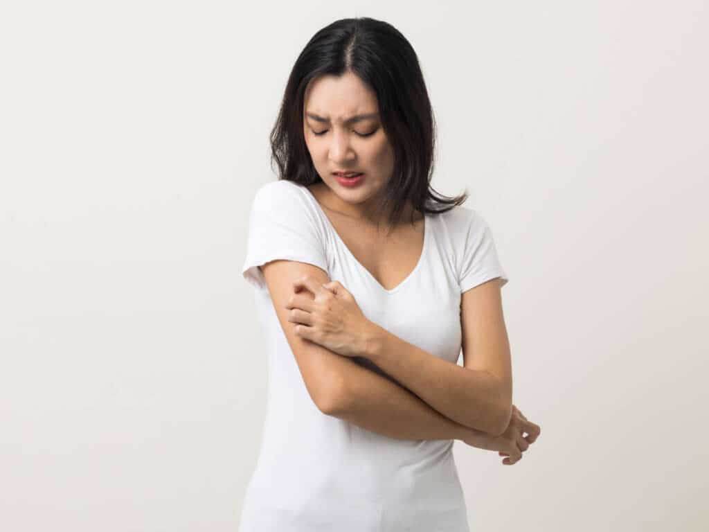 A woman scratching itchy bites from bedbugs