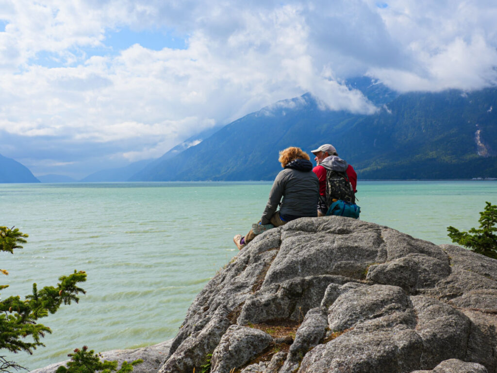 A couple admiring the waters of the Taiya Inlet from a rock