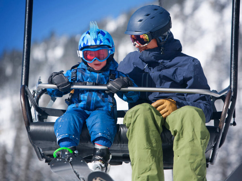 A kid with a man on a ski lift