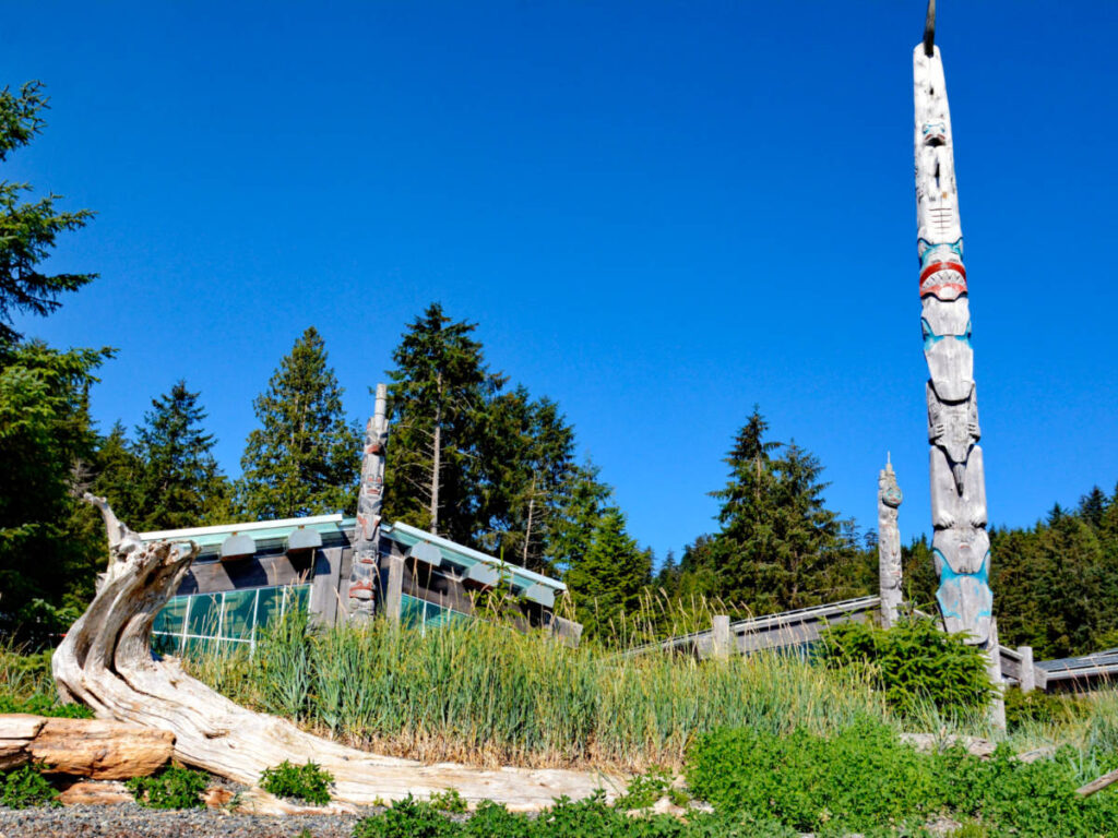 A totem pole standing tall amidst the lush forest of Skidegate, Haida Gwaii