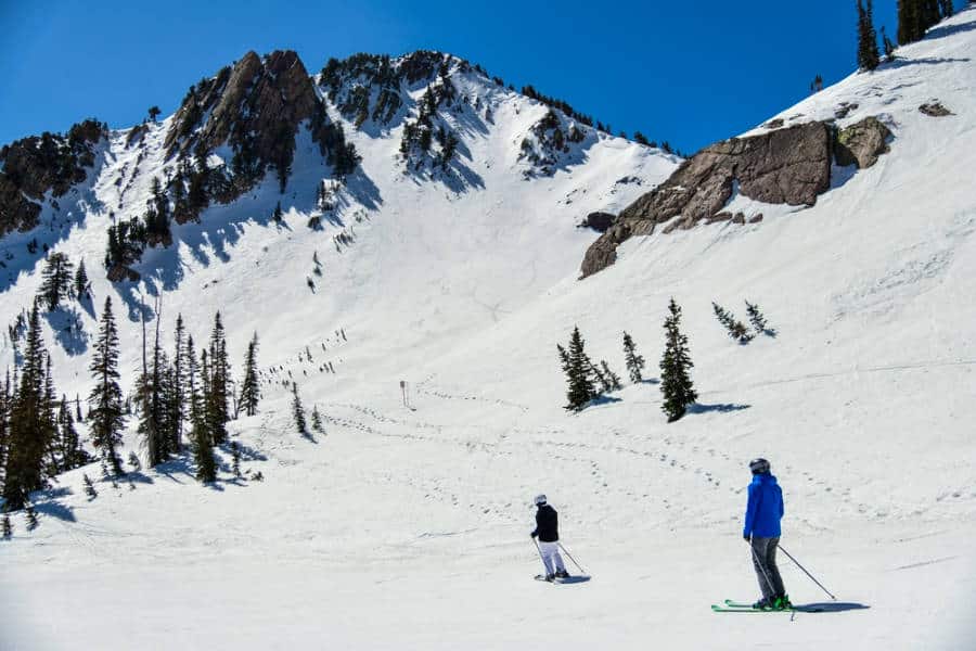 Skiers below the snow covered mountains at Snowbasin Ski Resort