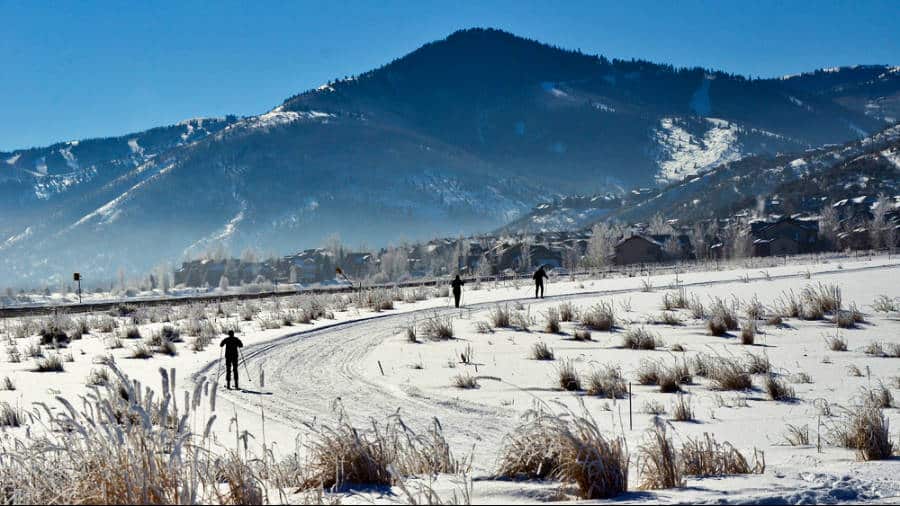 View of the skiers on a trail with mountains in the background